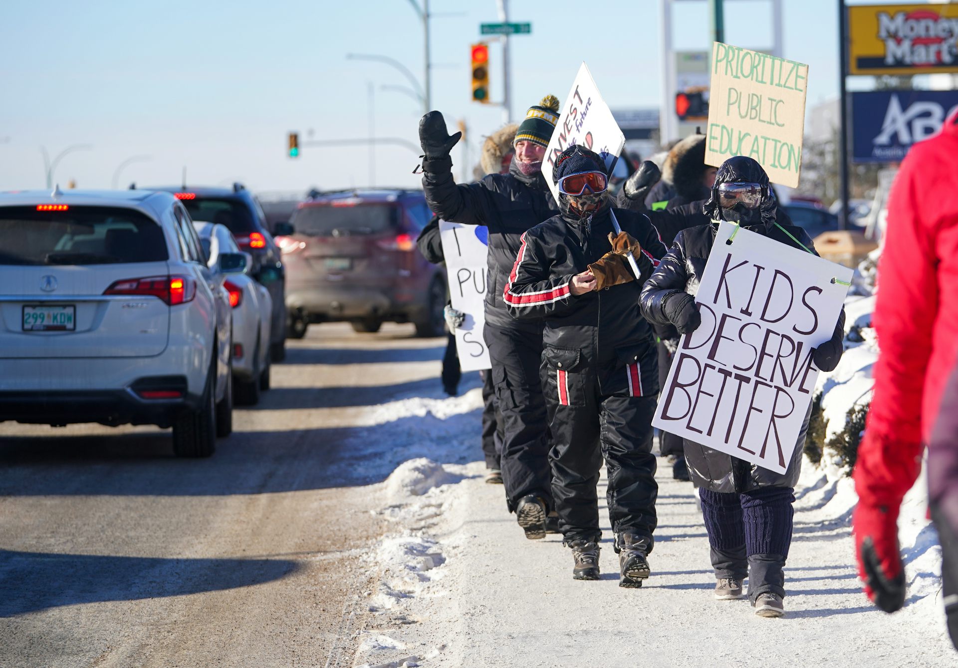 People seen on a picket line and one sign says kids are worth it.
