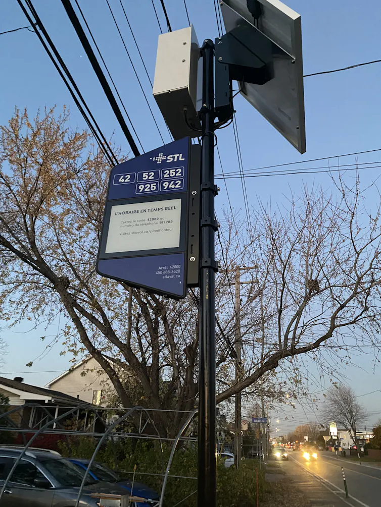 a bus stop sign with a solar-powered device attached to it