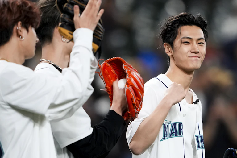 A person seen clenching a victory fist and smiling holding a baseball glove while others look on with gloves.