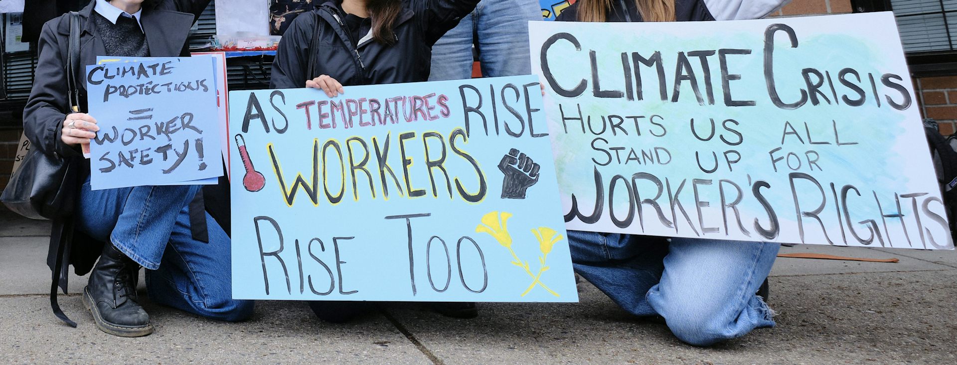 A group of people kneel with signs.