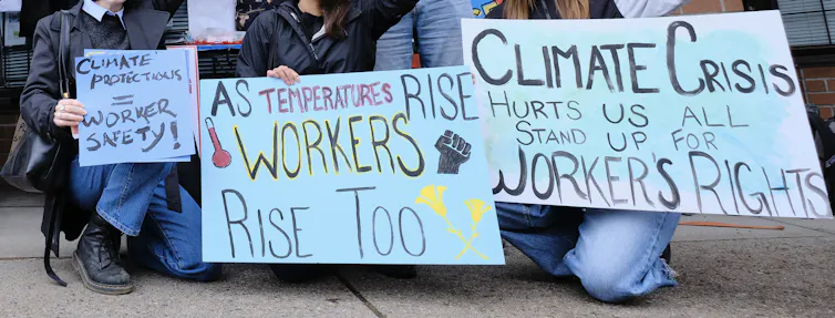 A group of people kneel with signs.
