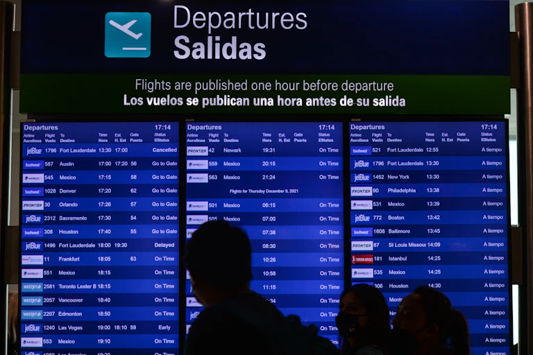 A blue sign displays departures. People are silhouetted in the foreground.