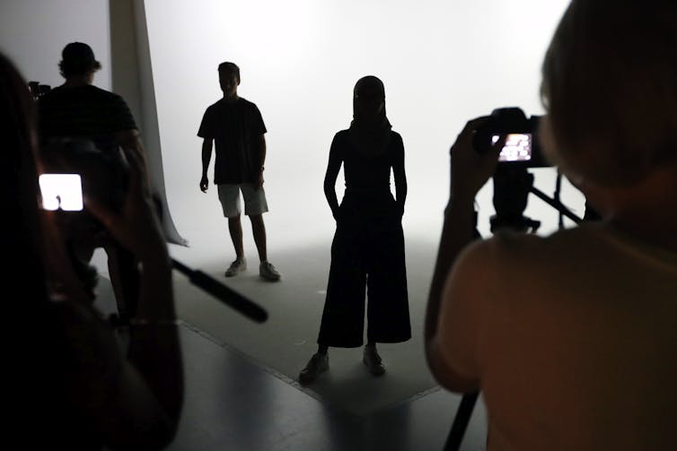 Silhouettes of people in front of a camera.