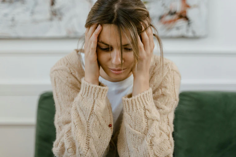 Distressed woman holds her head in her hands