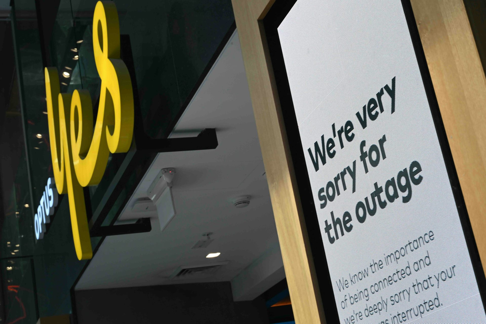 Photo of an Optus store with a sign outside reading "We're very sorry for the outage"