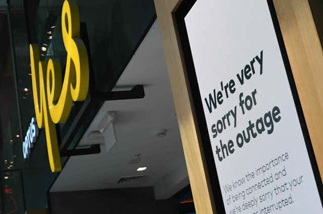 Photo of an Optus store with a sign outside reading "We're very sorry for the outage"
