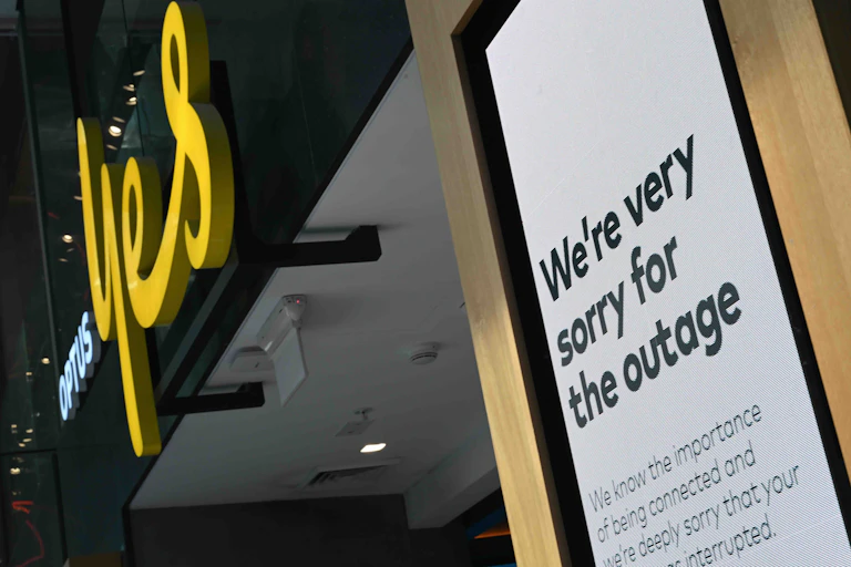Photo of an Optus store with a sign outside reading "We're very sorry for the outage"