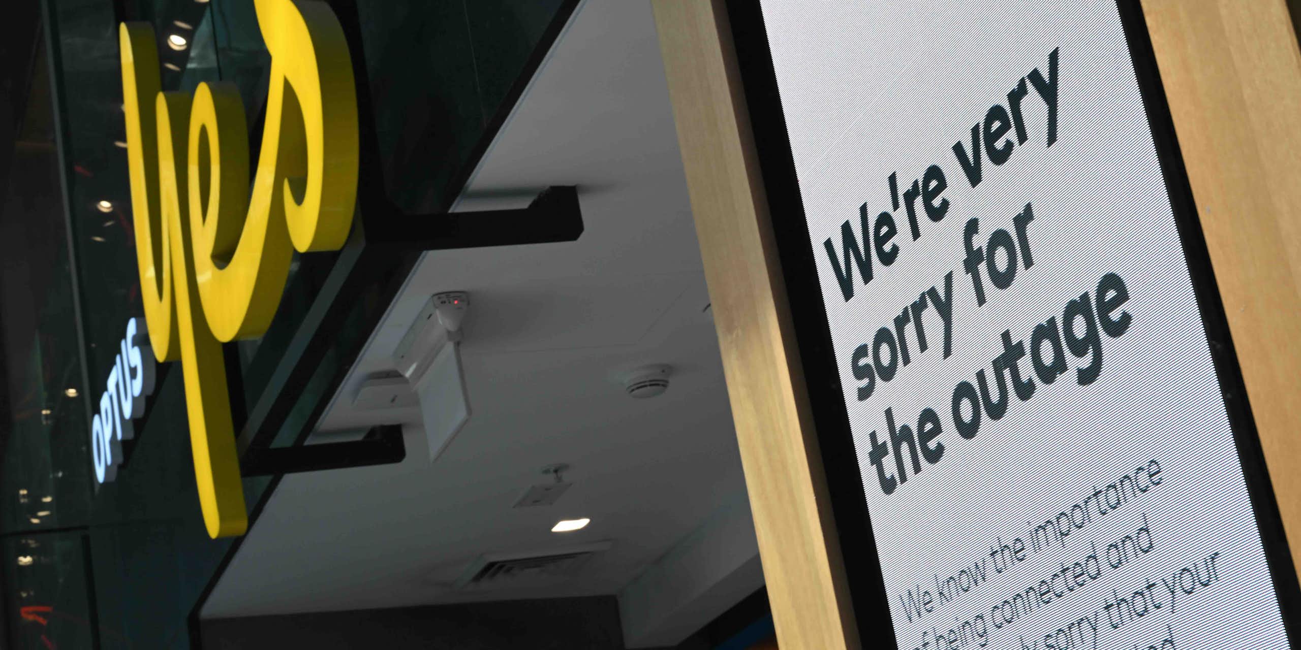 Photo of an Optus store with a sign outside reading "We're very sorry for the outage"