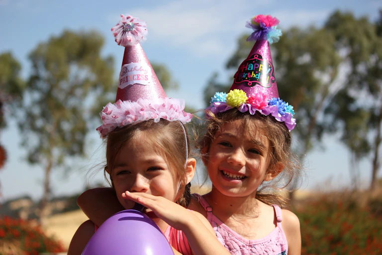 Girls wearing party hats smile