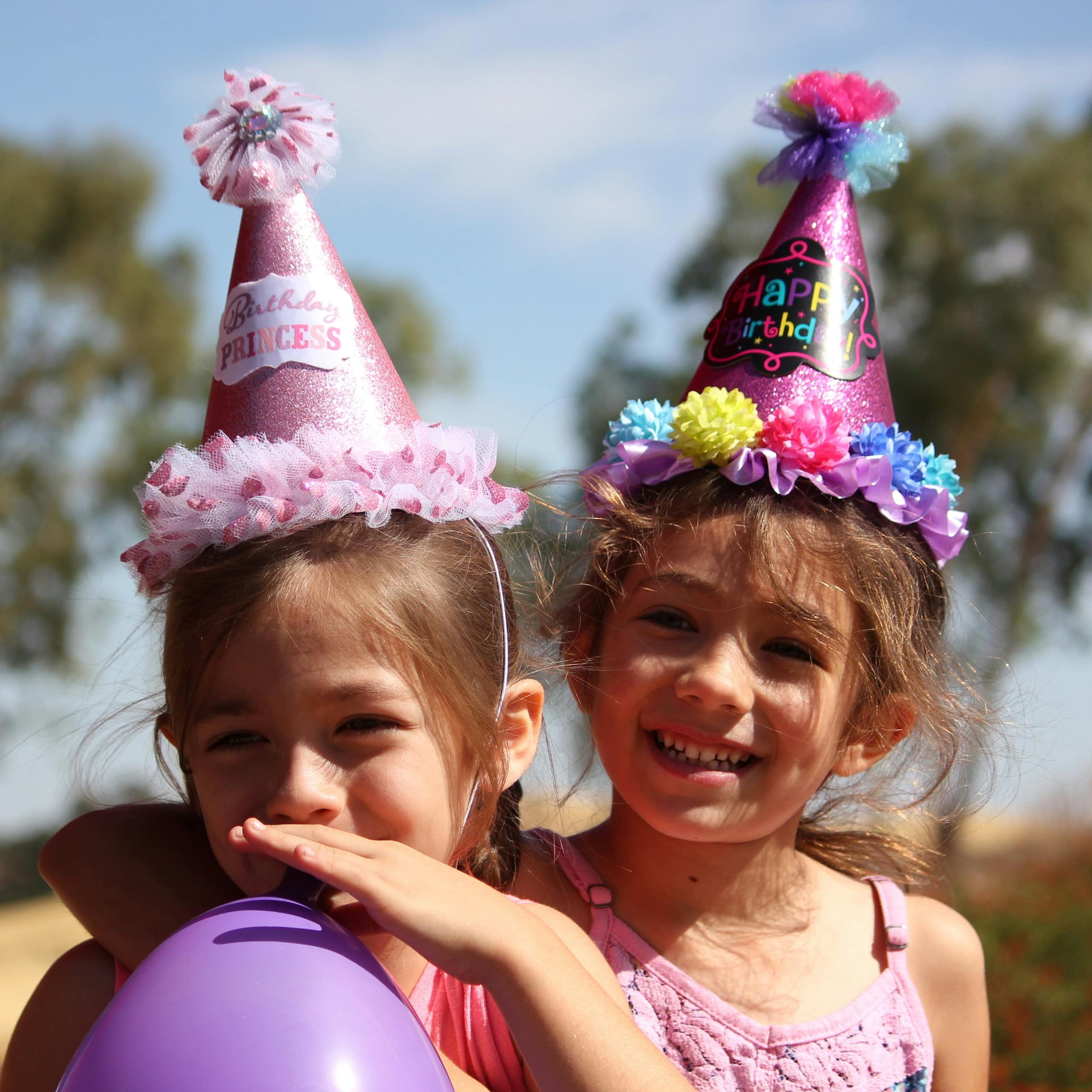 Girls wearing party hats smile