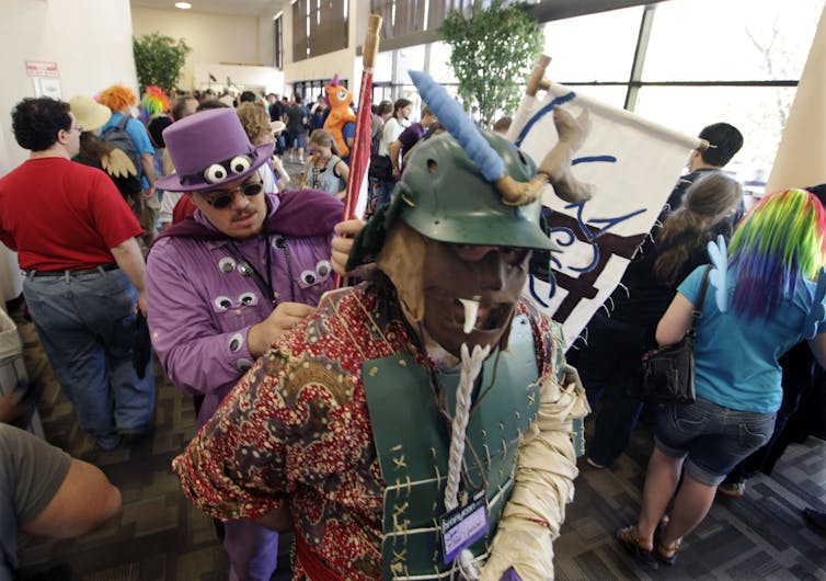 Two people dressed up in costumes are at a convention.