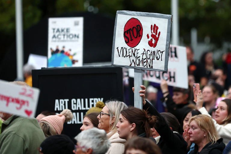 A protest with a sign reading STOP VIOLENCE AGAINST WOMEN