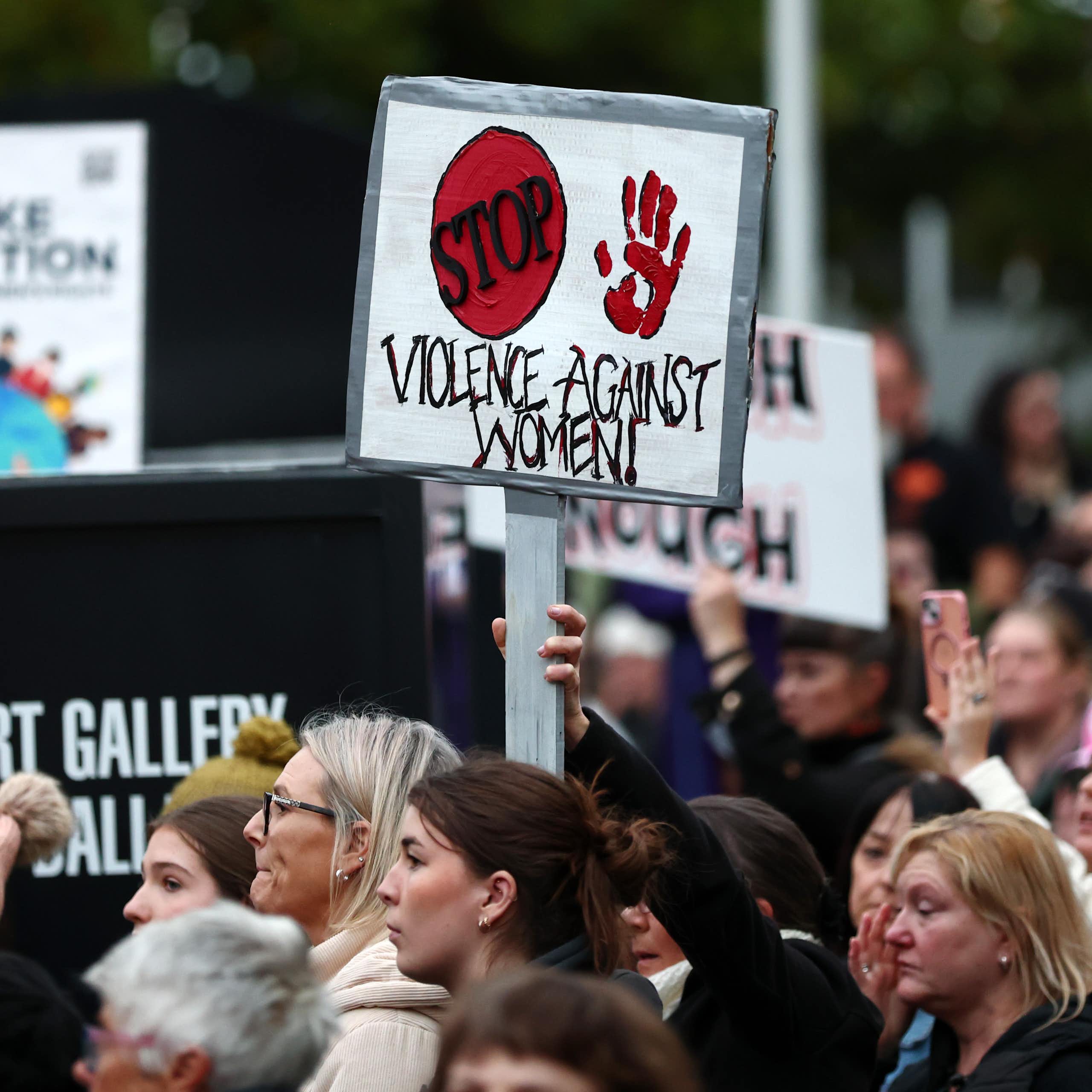 A protest with a sign reading STOP VIOLENCE AGAINST WOMEN