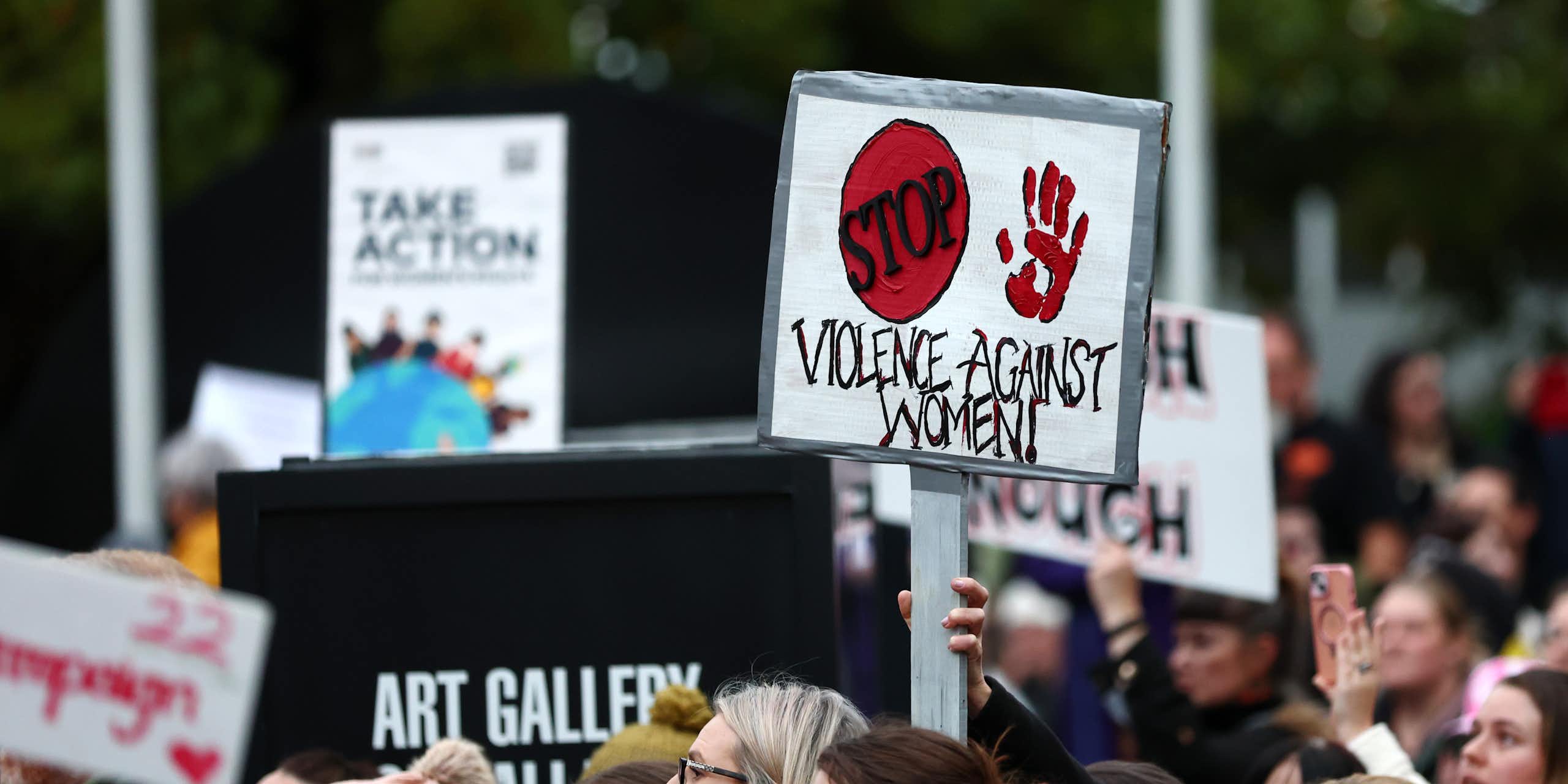A protest with a sign reading STOP VIOLENCE AGAINST WOMEN
