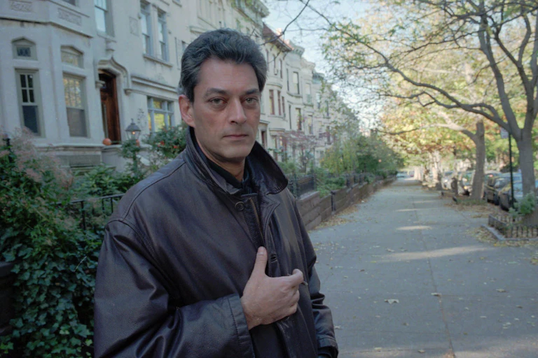 Paul Auster standing in a tree-lined street in Brooklyn