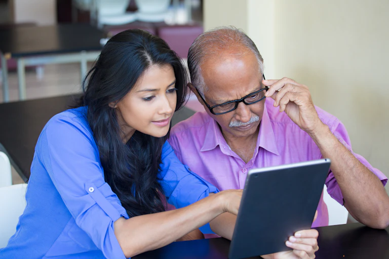 Young woman and older man looking at ipad.