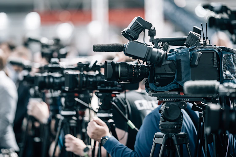 Side view of news cameras assembled at an event