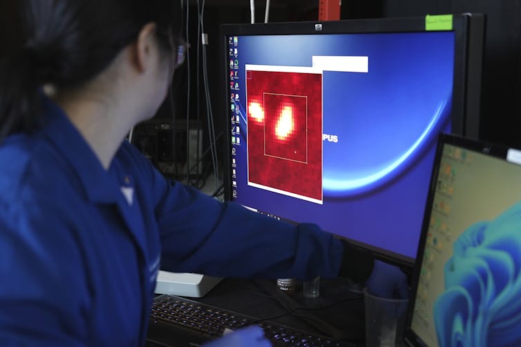 A scientist looks at a computer screen that shows an enlarged red area.