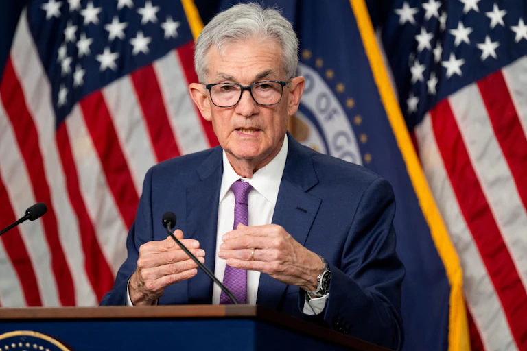 The chair of the Federal Reserve is seen standing behind a podium and in front of several American flags.