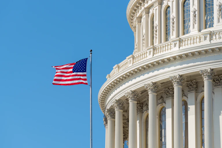 An American flag flying in front of a large, white and round building.