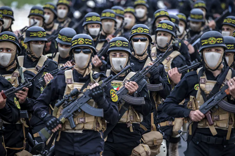 Armed fighters dressed in combat clothing on a march.
