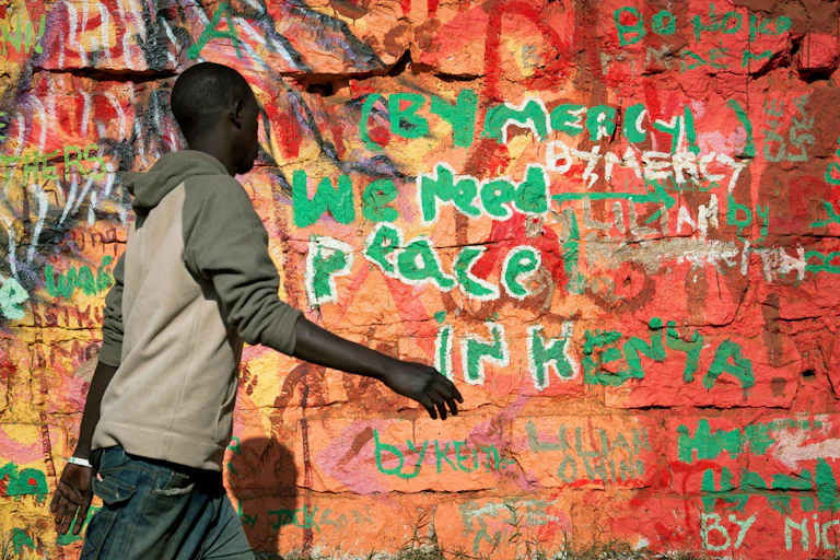 A man walking past a wall painted with several different colours.