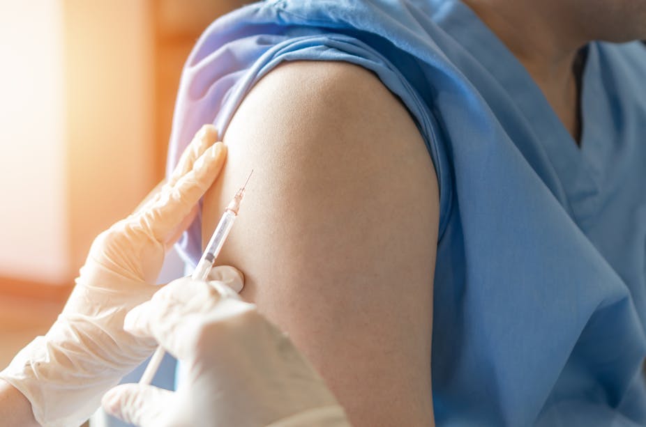 A doctor or nurse is about to give someone a vaccine in their arm. 