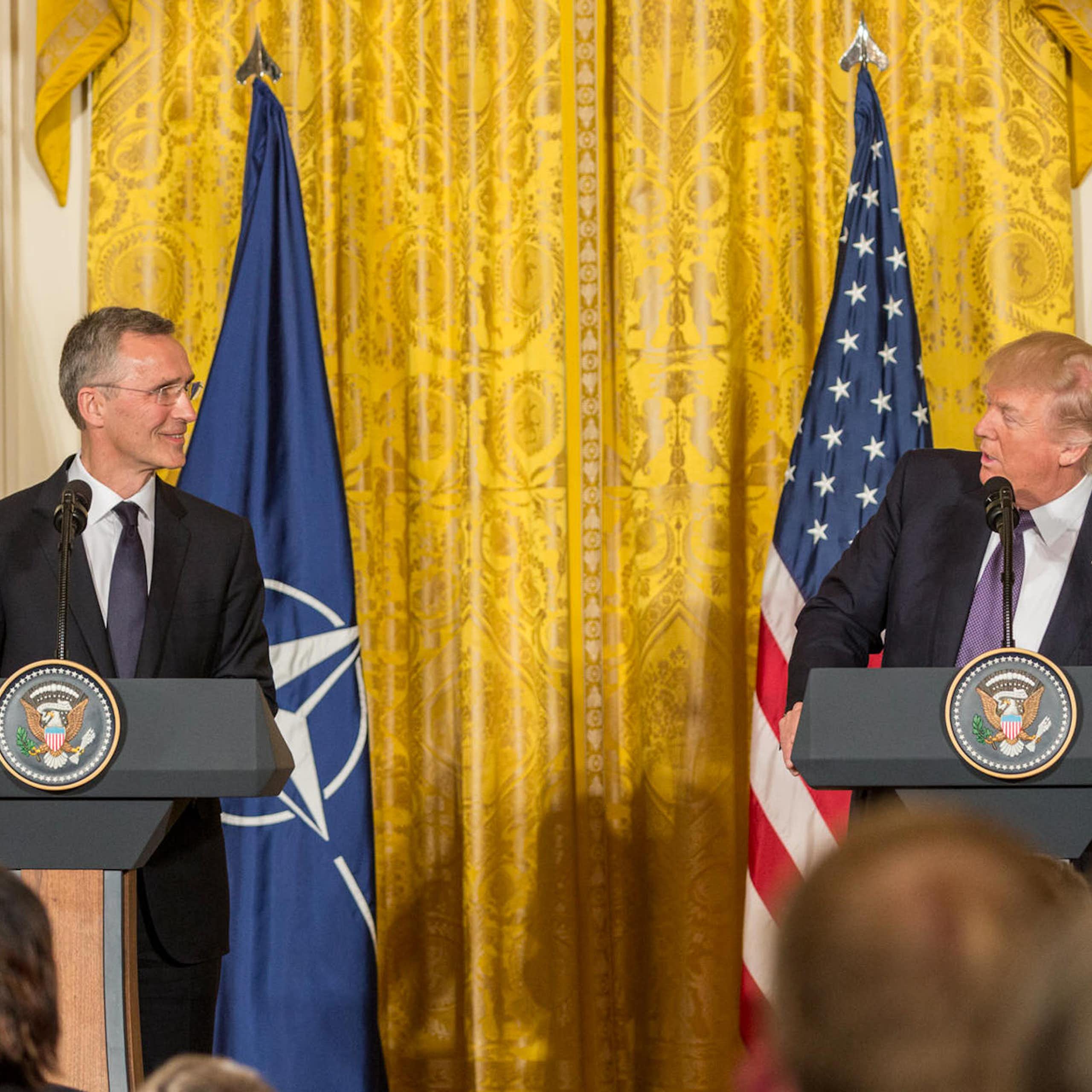 Donald Trump (right) and Jens Stolenberg standing in front of flags.