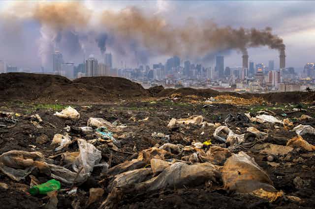 Waste on ground, polluting chimneys in background