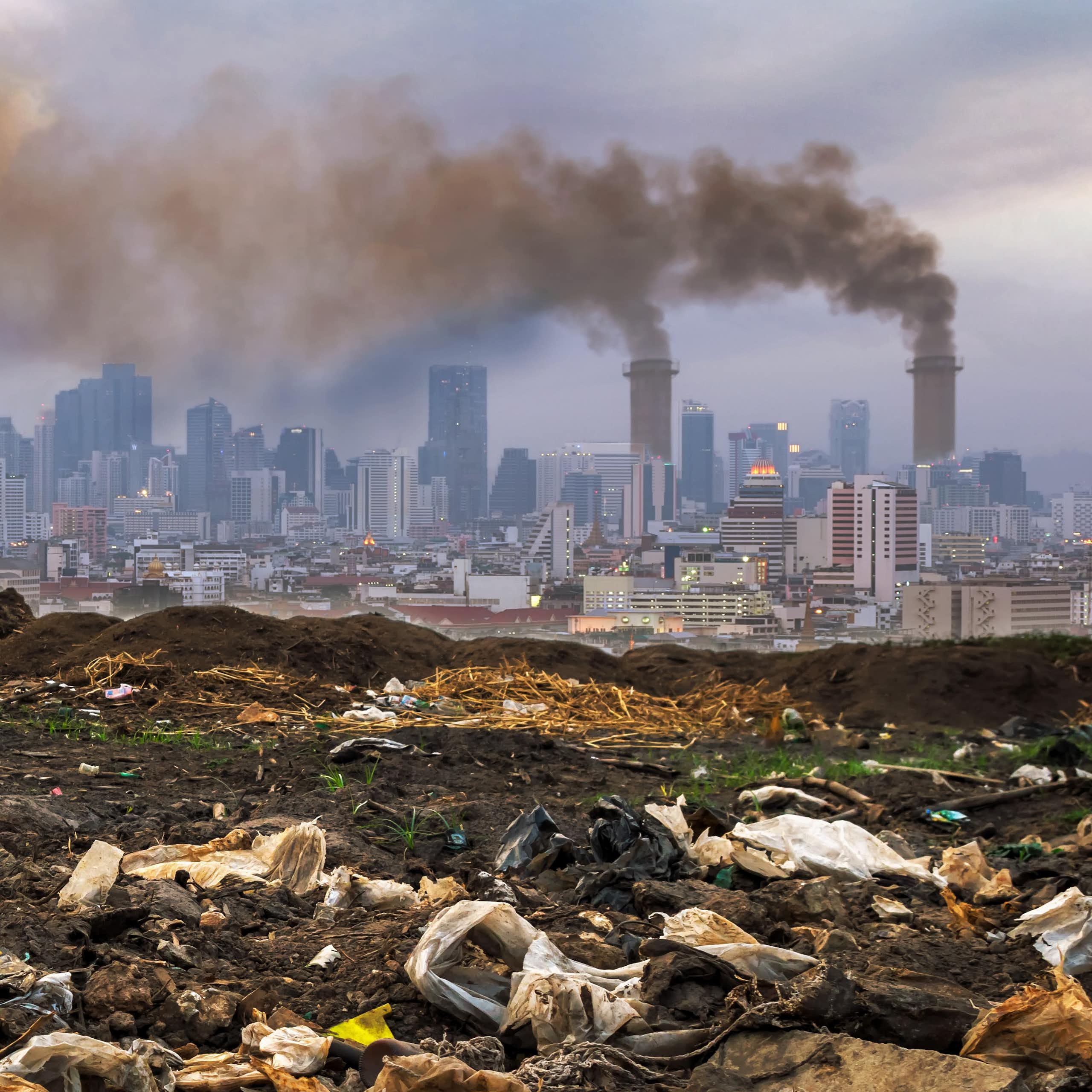 Waste on ground, polluting chimneys in background