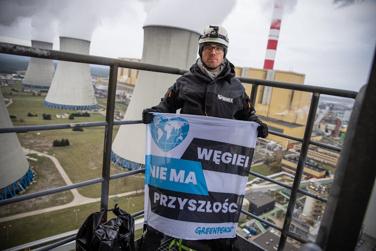 Man with banner, coal plant in background