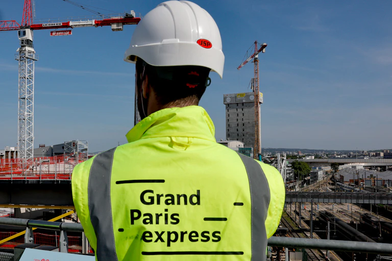 Un ouvrier regarde le chantier de la nouvelle gare Saint-Denis Pleyel du Grand Paris Express à Saint-Denis, au nord de Paris, le 30 mai 2023. Située à proximité du village olympique et du Stade de France, la gare Saint-Denis Pleyel est essentielle pour les Jeux Olympiques et reliera les futures lignes 14, 15, 16 et 17 du métro parisien au métro Grand Paris Express pour devenir à terme la plus grande gare du réseau Grand Paris Express, avec plus de 250 000 voyageurs par jour.