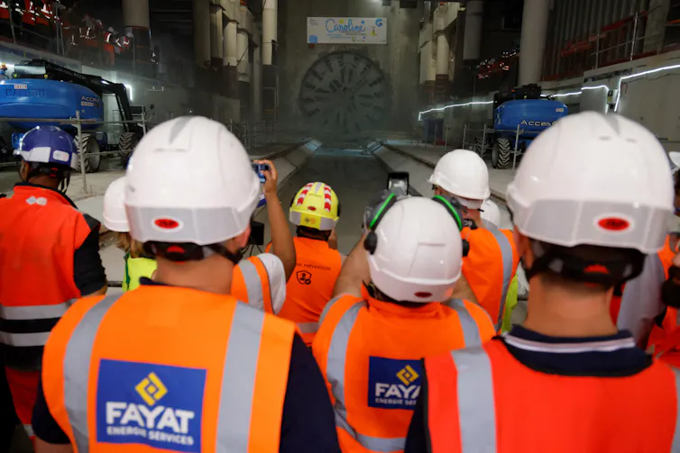 Des ouvriers regardent l’arrivée du tunnelier « Caroline » réalisant le tunnel de la 18ᵉ ligne du futur métro Grand Paris Express, le 13 juin 2023, à l’aéroport d’Orly, à Orly