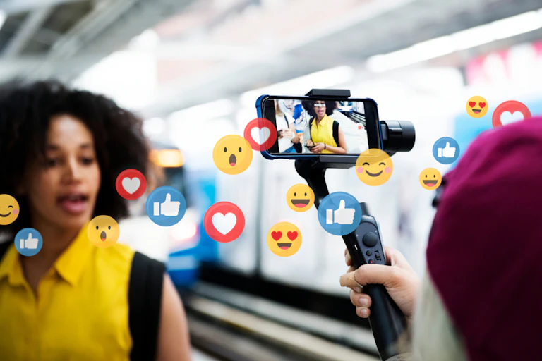 Une personne en train de se filmer dans une gare avec des dessins d'émojis