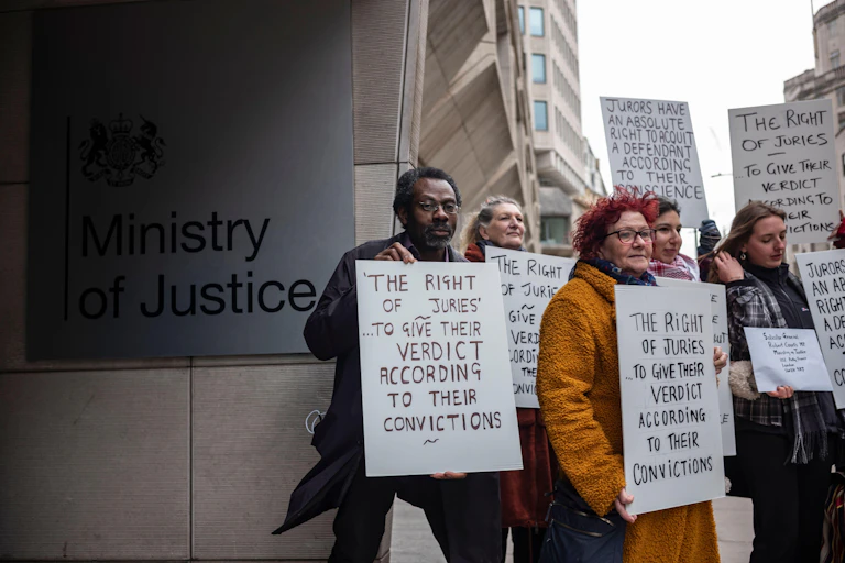 People hold signs outside Ministry of Justice building.