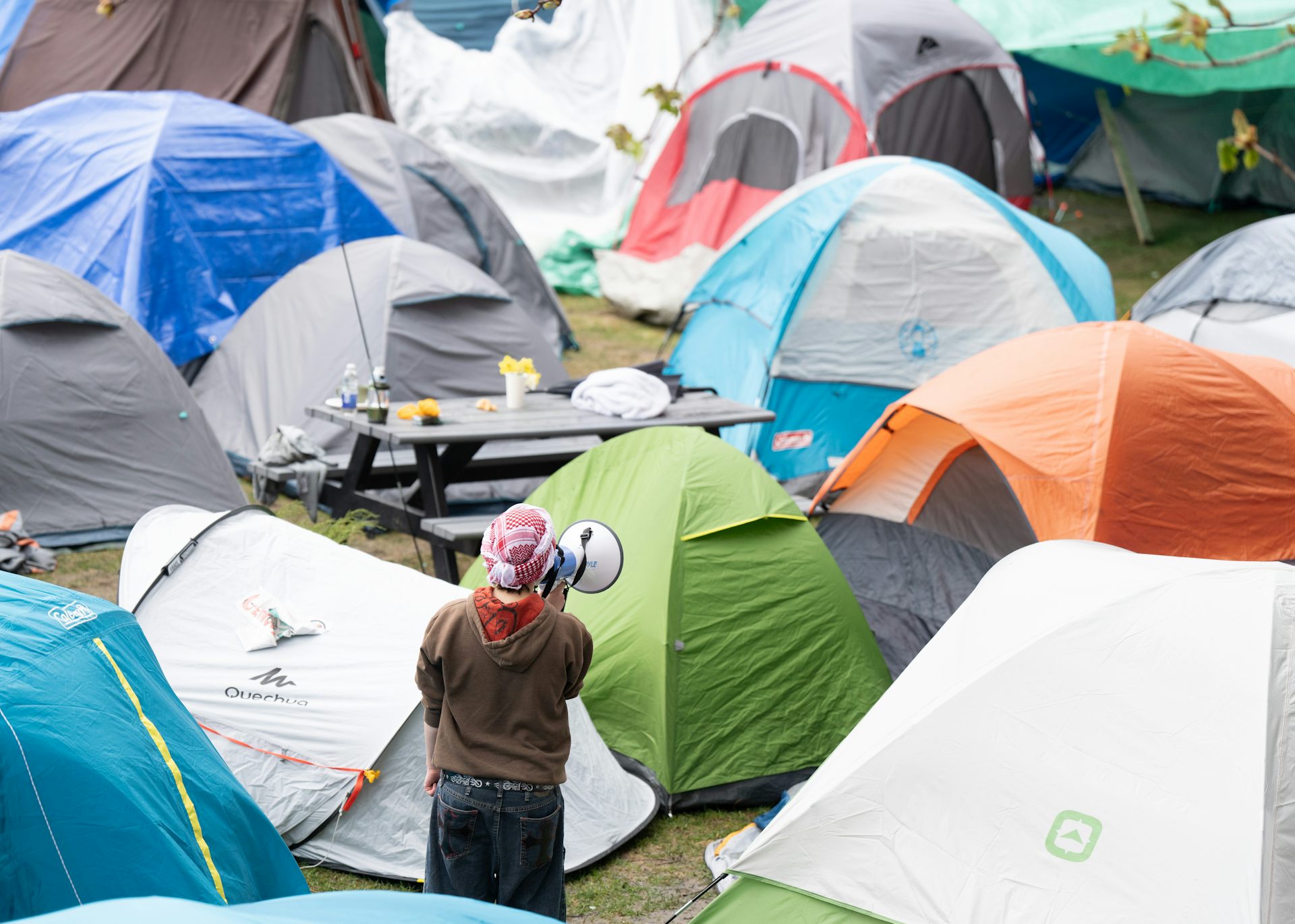 A protestor with a megaphone seen amid tents.