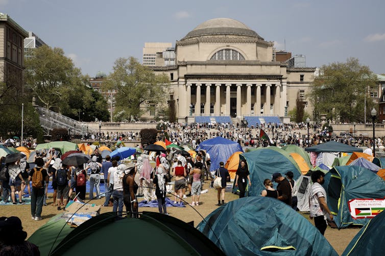 an encampment of young people in front of a stately looking university building