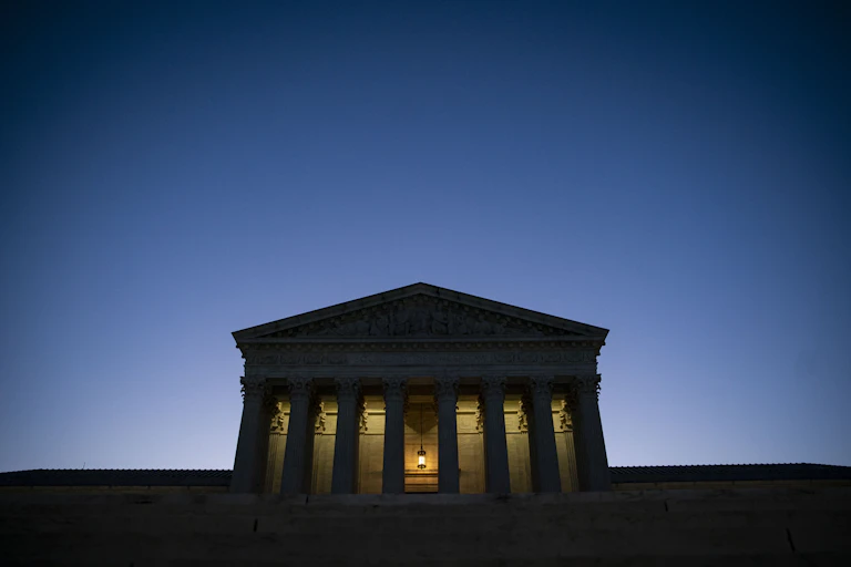 A large, columned building in front of a dark blue sky.