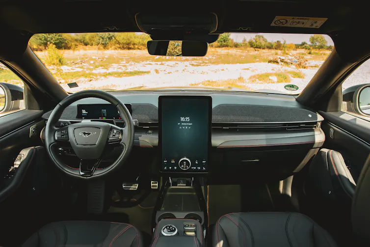 the inside of a vehicle with a country road visible through the windshield