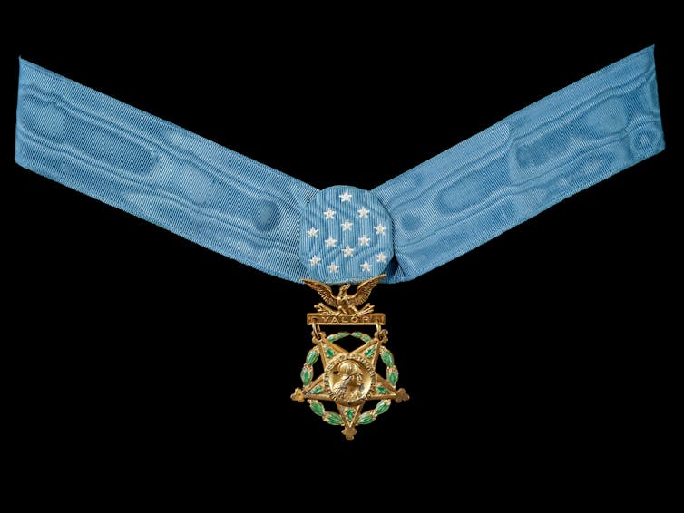 A blue ribbon with a gold star hanging from a blue clasp with 13 white stars.