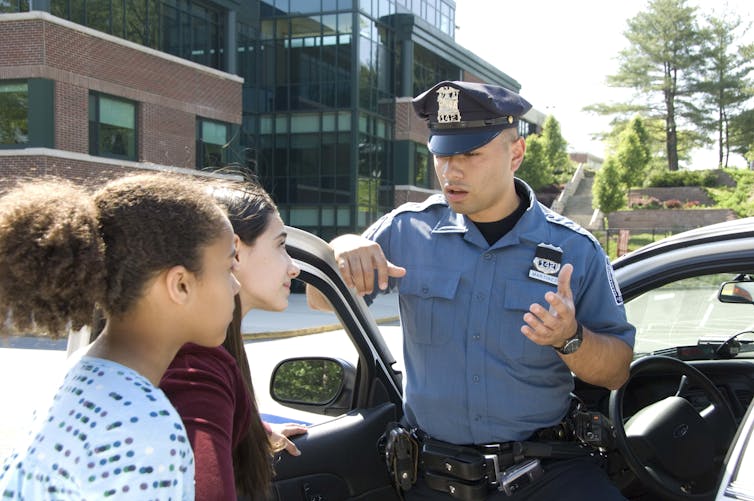Police officer speaks with two young girls.