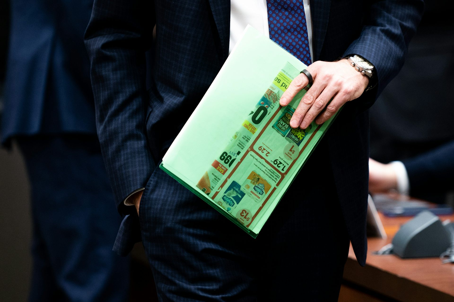 A close up of a hand holding a grocery flyer