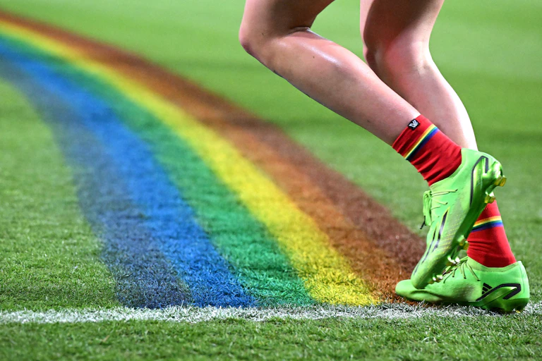 An AFLW player runs across a rainbow 50m arc
