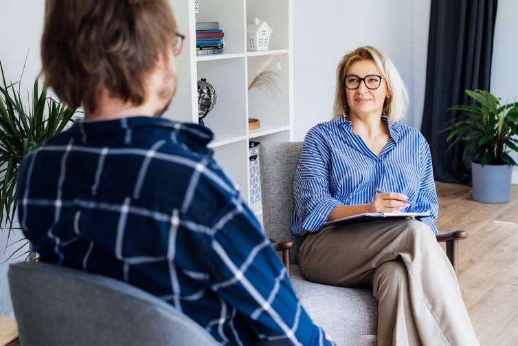 A female psychologist or counselor talks to a male patient