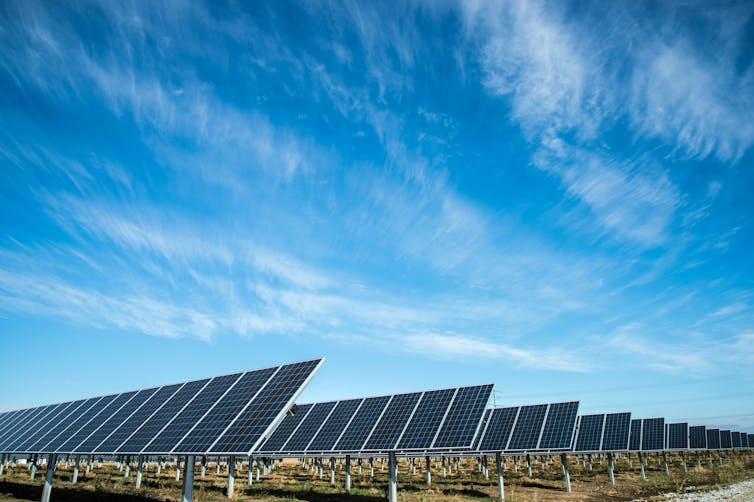 Photo of an array of solar panels under a blue sky.