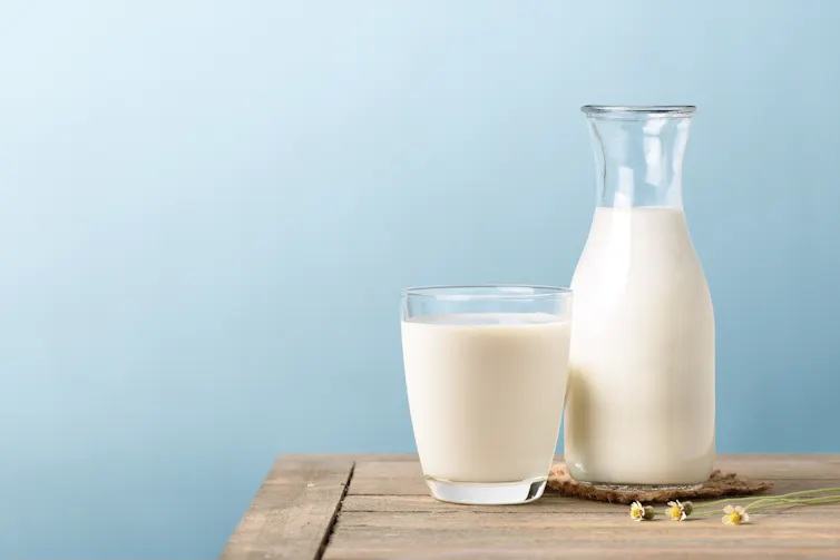 Photo of a glass and a bottle of milk on a bench.