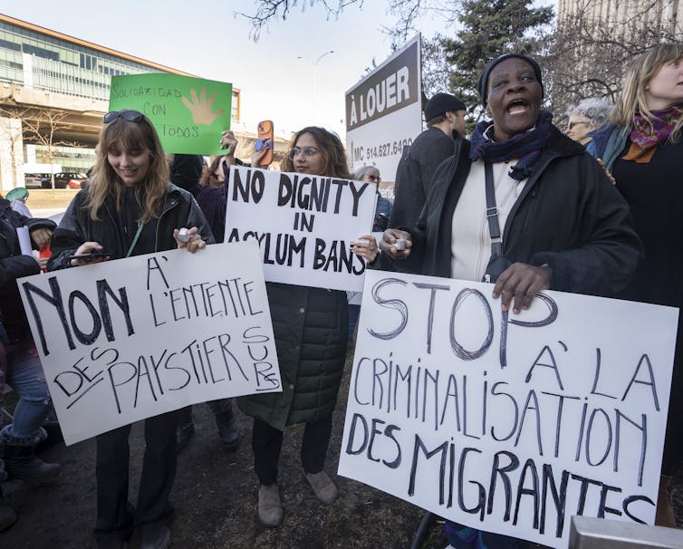 People carry signs at a protest. One reads: No dignity in asylum bans