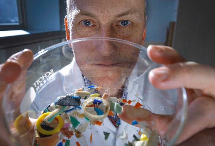 close up shot face of man with glass jar with tiny plastic fragments