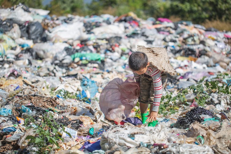 Een kind doorzoekt plastic op een vuilstortplaats.