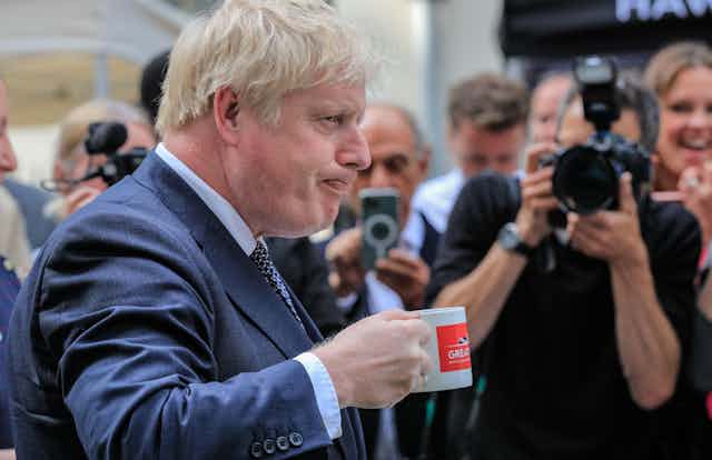 Boris Johnson drinking from a mug.